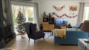 Una sala de estar con chimenea, un sofá azul, un televisor y un árbol de Navidad.