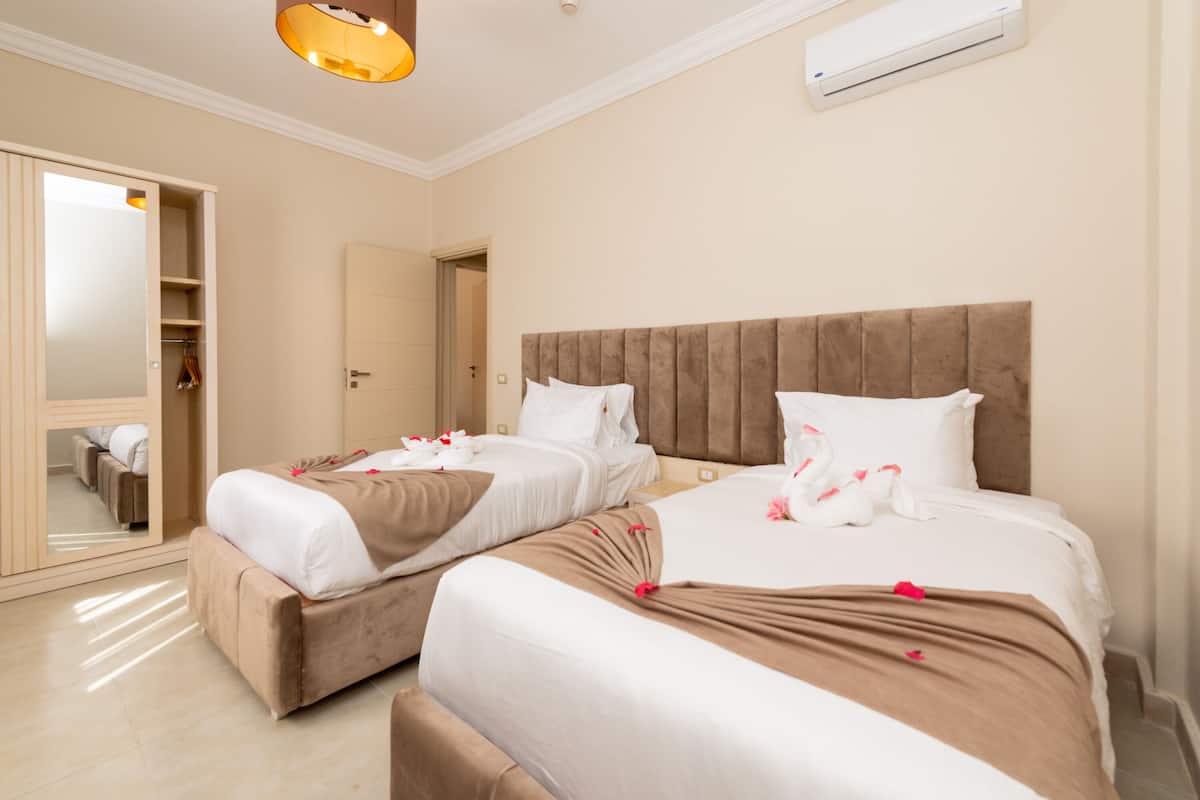 Habitación de hotel con dos camas, un armario, un espejo y un equipo de aire acondicionado.