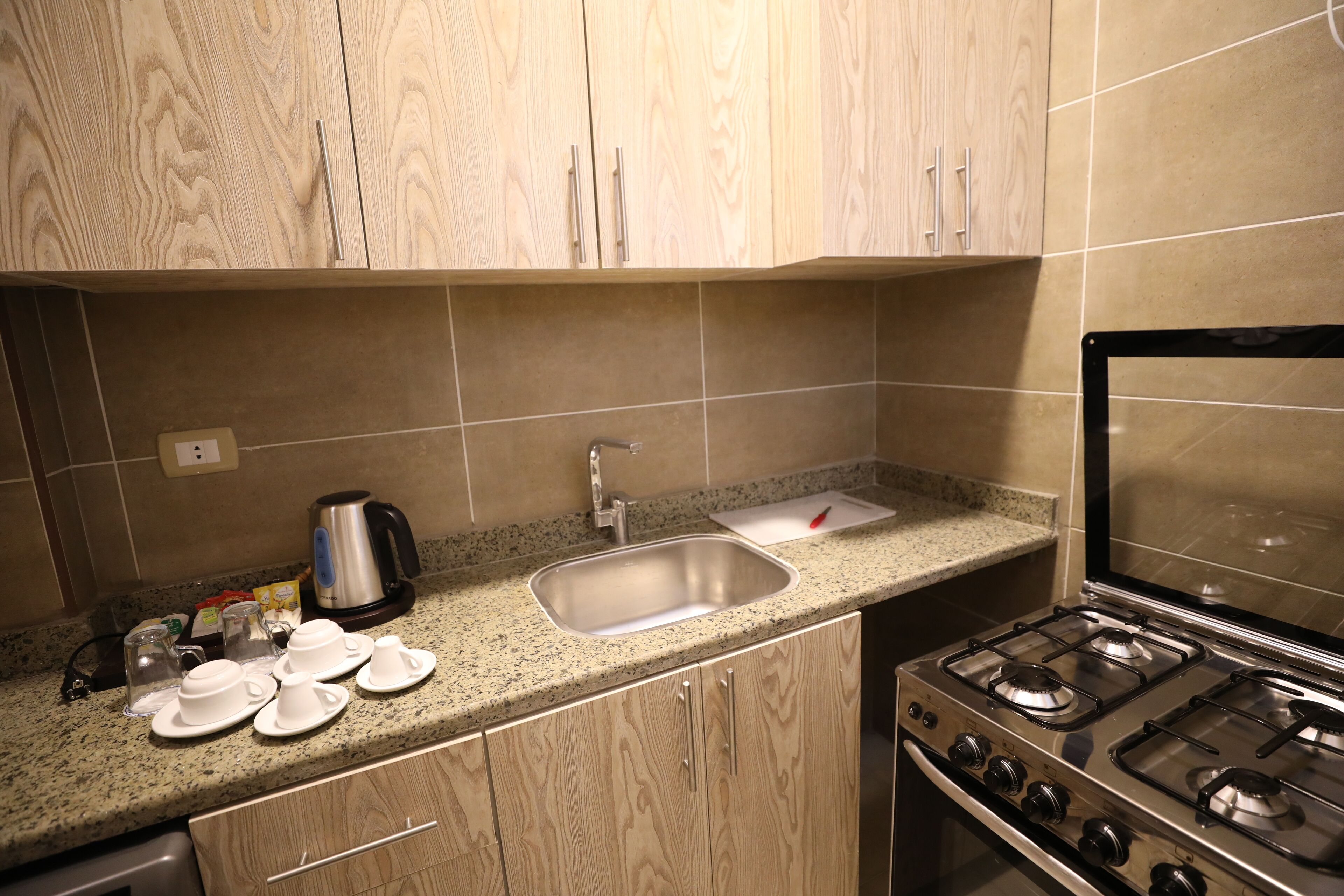 A kitchen with wooden cabinets, a stainless steel sink, a gas stove, and a coffee maker.