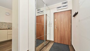 Une pièce avec une armoire en bois, un miroir, une horloge et un mur recouvert de carreaux.