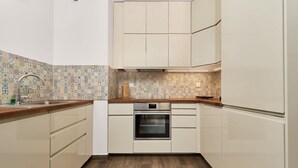 Une cuisine avec un crédence à motifs, un plan de travail en bois et des appareils électroménagers intégrés.