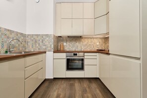Eine Küche mit gemustertem Fliesenspiegel, Holz Arbeitsplatte und eingebauten Geräten.