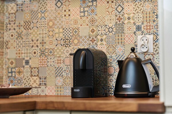 A kitchen with a patterned backsplash, a kettle, and a coffee maker on the counter.