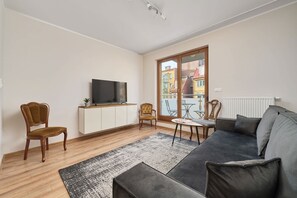 A modern living room with a sofa, chairs, a TV, and a dining table.