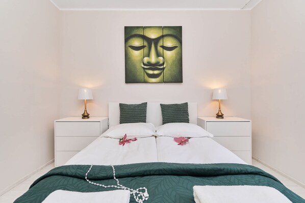 A bedroom with a bed, two bedside tables, a wall-mounted artwork, and a green and white color scheme.
