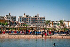 Aan een privéstrand, ligstoelen, parasols, beachvolleybal