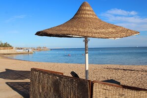Aan een privéstrand, ligstoelen, parasols, beachvolleybal