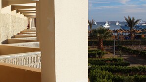 Un balcón de hotel con vistas al mar, barcos y una palmera.