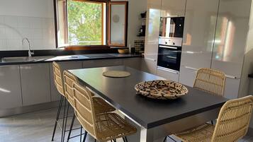 Une cuisine moderne dotée d’un îlot central, d’appareils électroménagers intégrés et d’une grande fenêtre.
