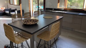 Cozinha moderna com ilha central, cadeiras de jantar e vista para o exterior.