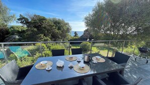 Mesa posta ao ar livre com vista para o mar e vegetação.