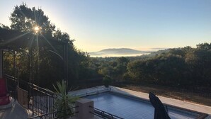 A rooftop pool with a view of a forested landscape and distant hills.