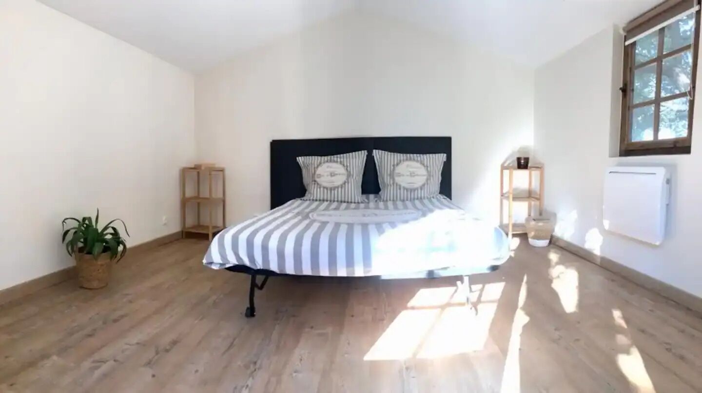 Un dormitorio con una cama, una planta en maceta, un ventanal y un radiador.