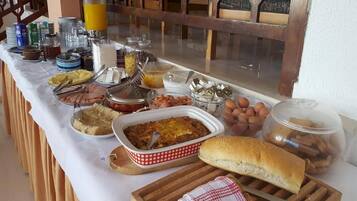 Una mesa de buffet con distintos alimentos, entre ellos, un plato al horno, huevos y una baguette.