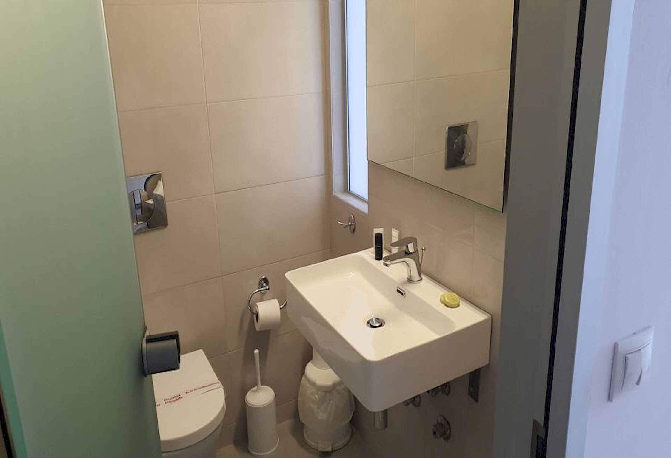 A bathroom with a white sink, toilet, and a window.
