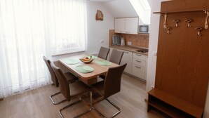 Una cocina moderna con comedor, que incluye una mesa de madera, sillas y un microondas.