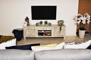 Relax in this stylish living room with a flat-screen TV, comfortable sofa, and a beautiful potted plant.