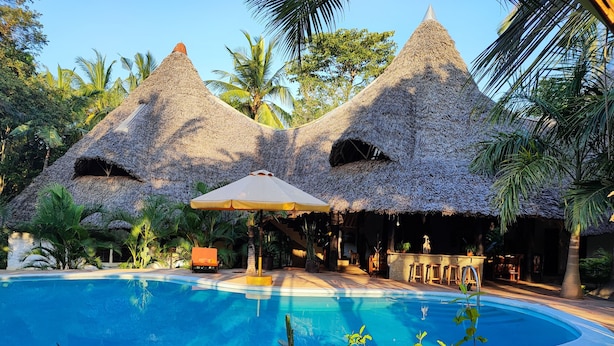 A pool area with thatched-roof structures and a lounge area. - Villa Mongoose Forest Dream Resort (Diani Beach)