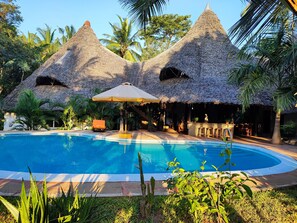 Un área de piscina con estructuras de techo de paja y una zona de estar.