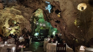 An underground restaurant with tables and chairs arranged in a cave-like setting, illuminated by hanging lanterns. - Villa Mongoose Forest Dream Resort (Diani Beach)