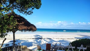 A beach with a thatched-roof structure, stone steps, and wooden lounge chairs. - Villa Mongoose Forest Dream Resort (Diani Beach)