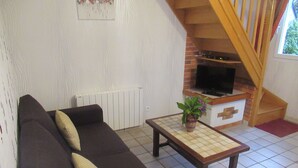 Una sala de estar con un sofá, una mesita con una planta, una chimenea y una escalera.