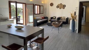A modern open-plan living area with a kitchen, dining table, and seating. - Villa Carla (Olmeto)