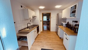Une cuisine de taille réduite avec des meubles blancs, un plan de travail en bois et un tapis noir sur le sol.