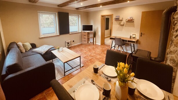 Un salon moderne avec un canapé, une table à manger pour deux personnes et un téléviseur.