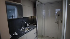 A narrow kitchen with a black countertop, stainless steel sink, and a white door. - Rawsheh 51 (Beirut)