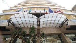 A hotel entrance with a modern design, featuring a large overhang and multiple flags. - Rawsheh 51 (Beirut)