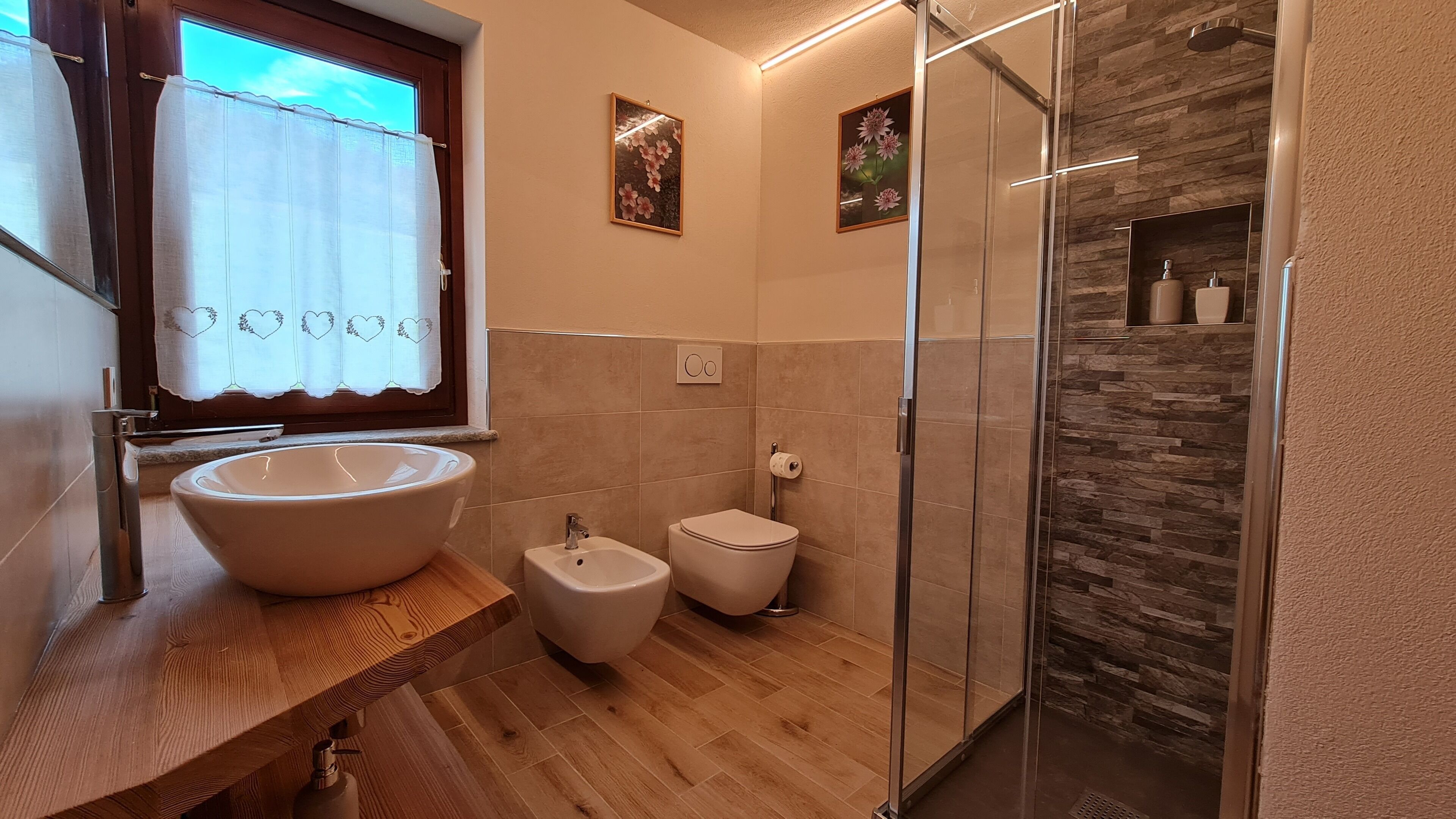 A bathroom with a large sink, a bidet, a toilet, and a glass shower enclosure.
