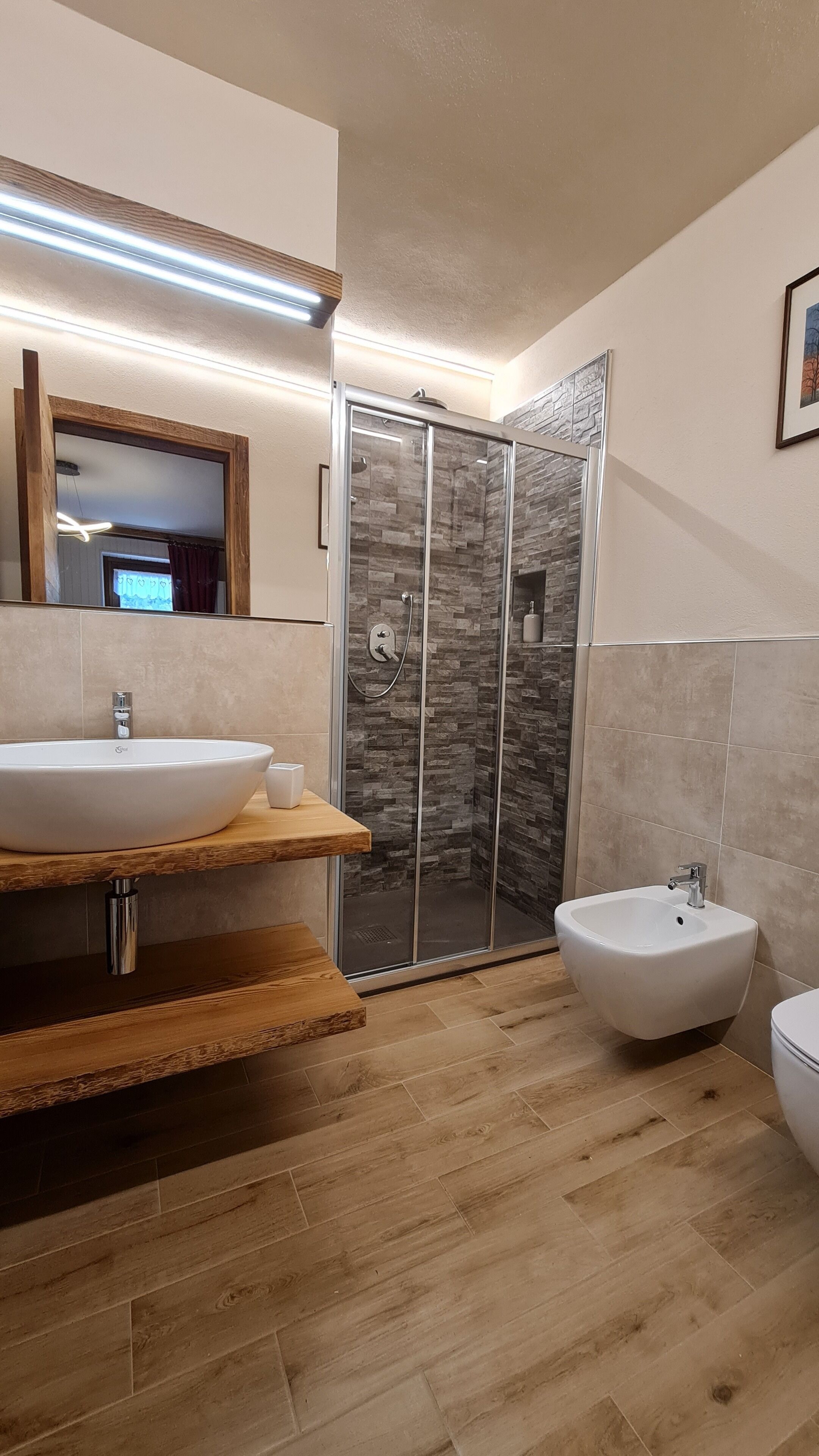 A modern bathroom with a large sink, a bidet, and a glass-enclosed shower.