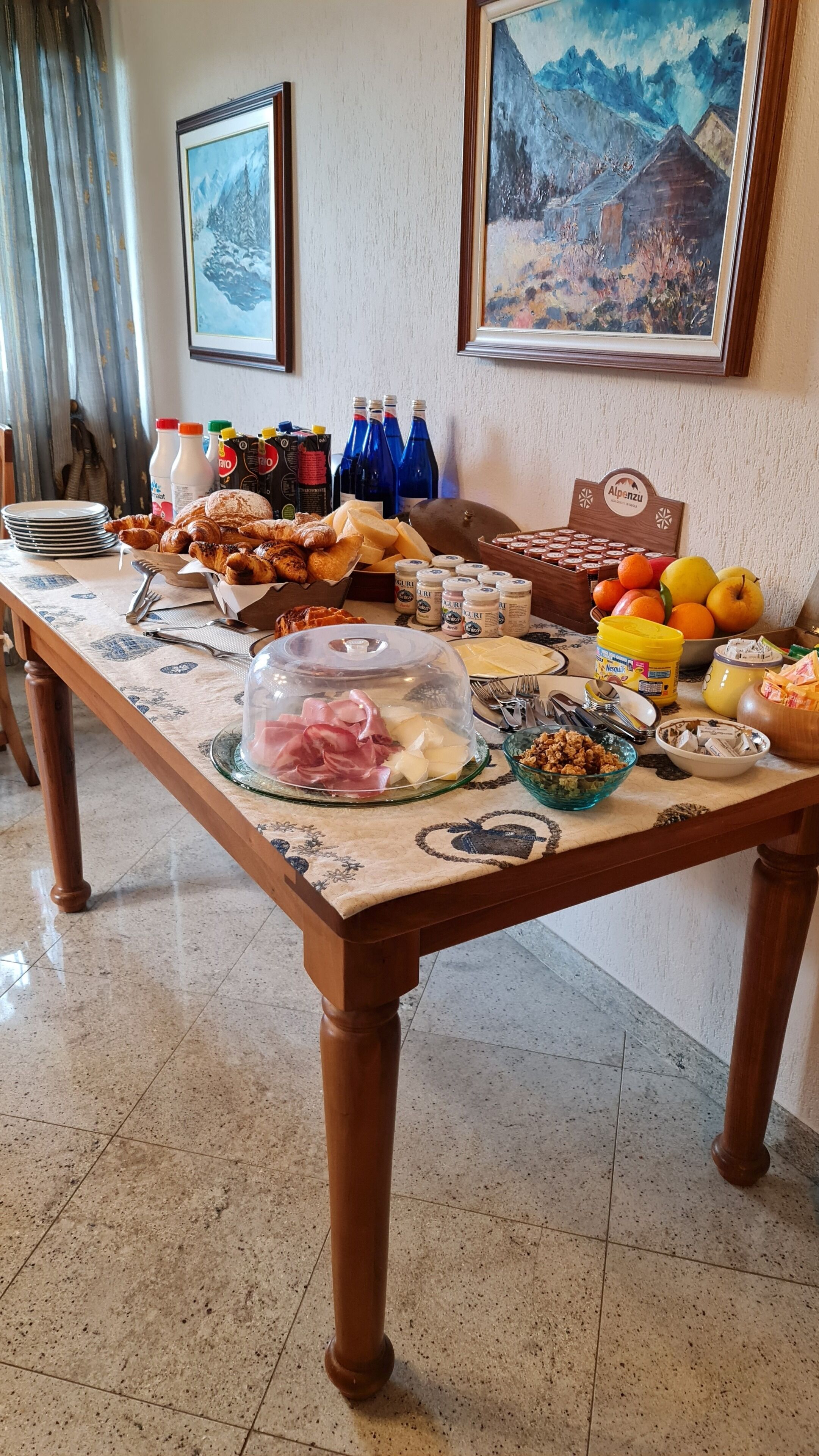 Een ontbijtbuffet met diverse soorten eten, zoals gebak, vleeswaren, kazen en fruit.