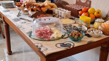 A breakfast buffet table with various food items, including pastries, meats, cheeses, and fruits.