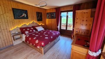 Ein Schlafzimmer mit Holzvertäfelung, einem Bett, einer Kommode und zwei Bildern an der Wand.