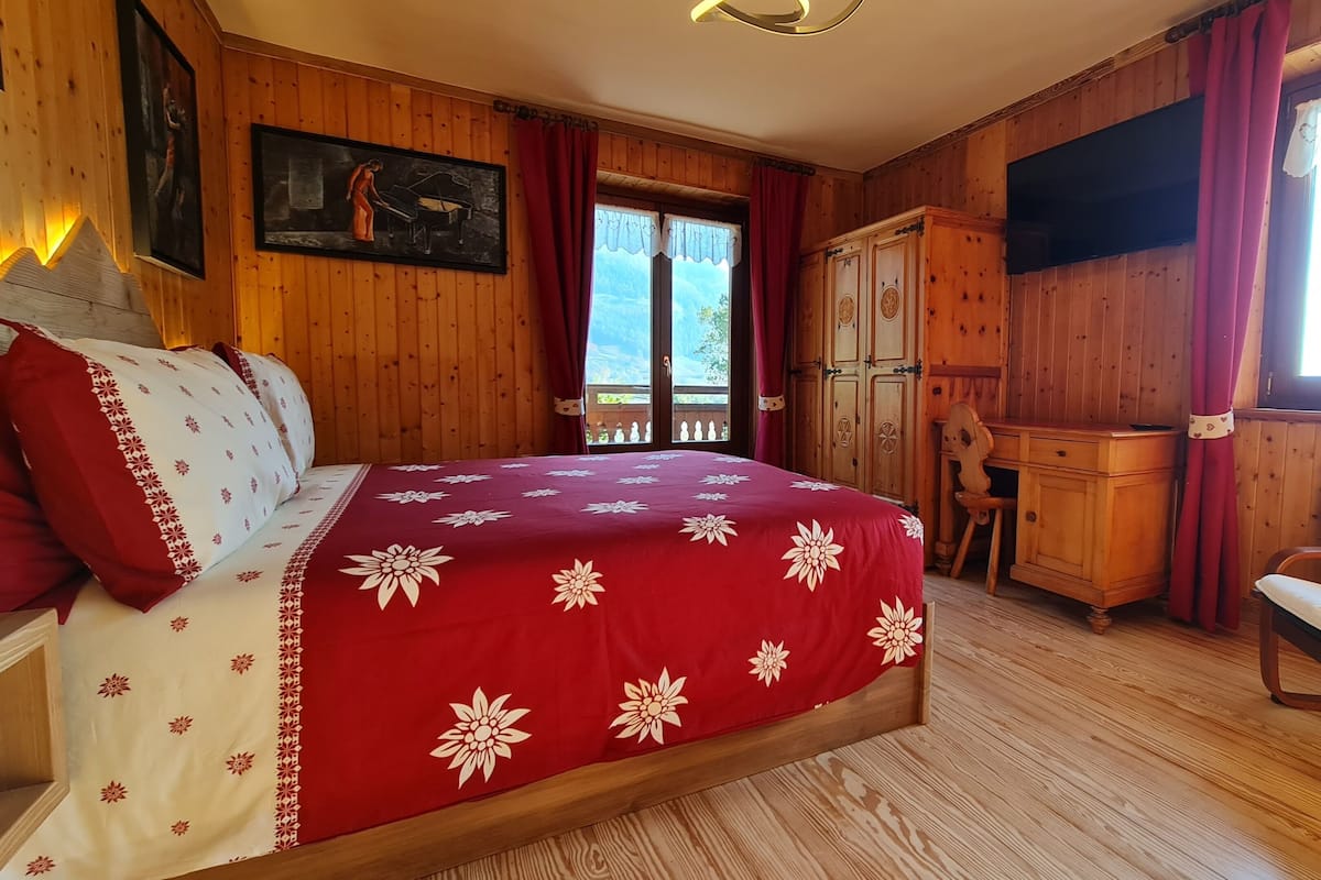 A wooden room with a bed, a desk, and a TV.