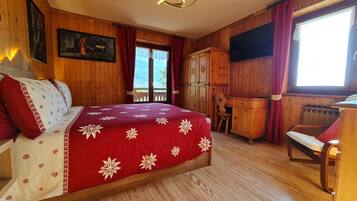 Ein Zimmer aus Holz mit einem Bett, einem Schreibtisch und einem Fernseher.