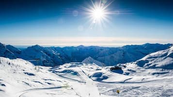 A snow-covered mountain landscape with a clear sky and a bright sun.
