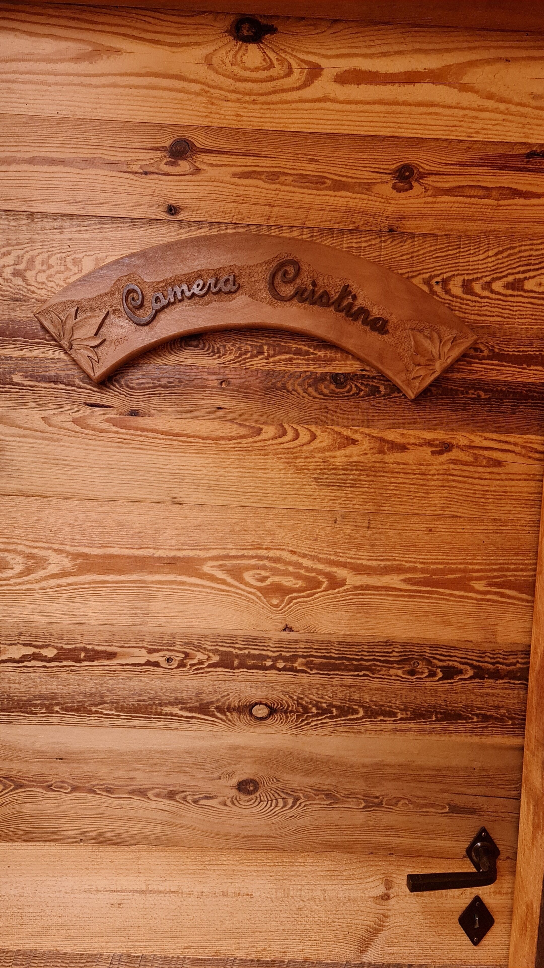 Una puerta de madera con una placa tallada que dice "Camira Cristina".