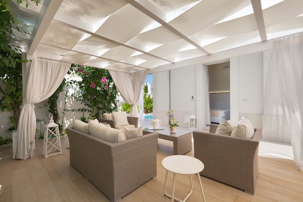 A covered outdoor seating area with wicker furniture, a table, and a lantern. - 2493 Acquaviva Suites - Matrimoniale Standard (Diso)