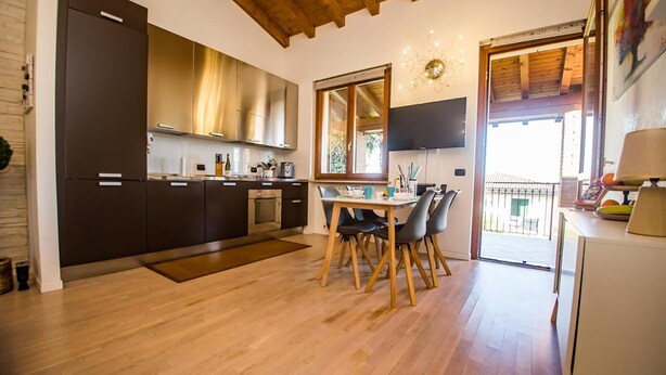 Une cuisine moderne avec des meubles de rangement sombres, une table à manger en bois et une grande fenêtre.