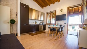 Une cuisine moderne avec des meubles sombres, un coin repas avec une table et des chaises en bois, et un balcon avec vue.