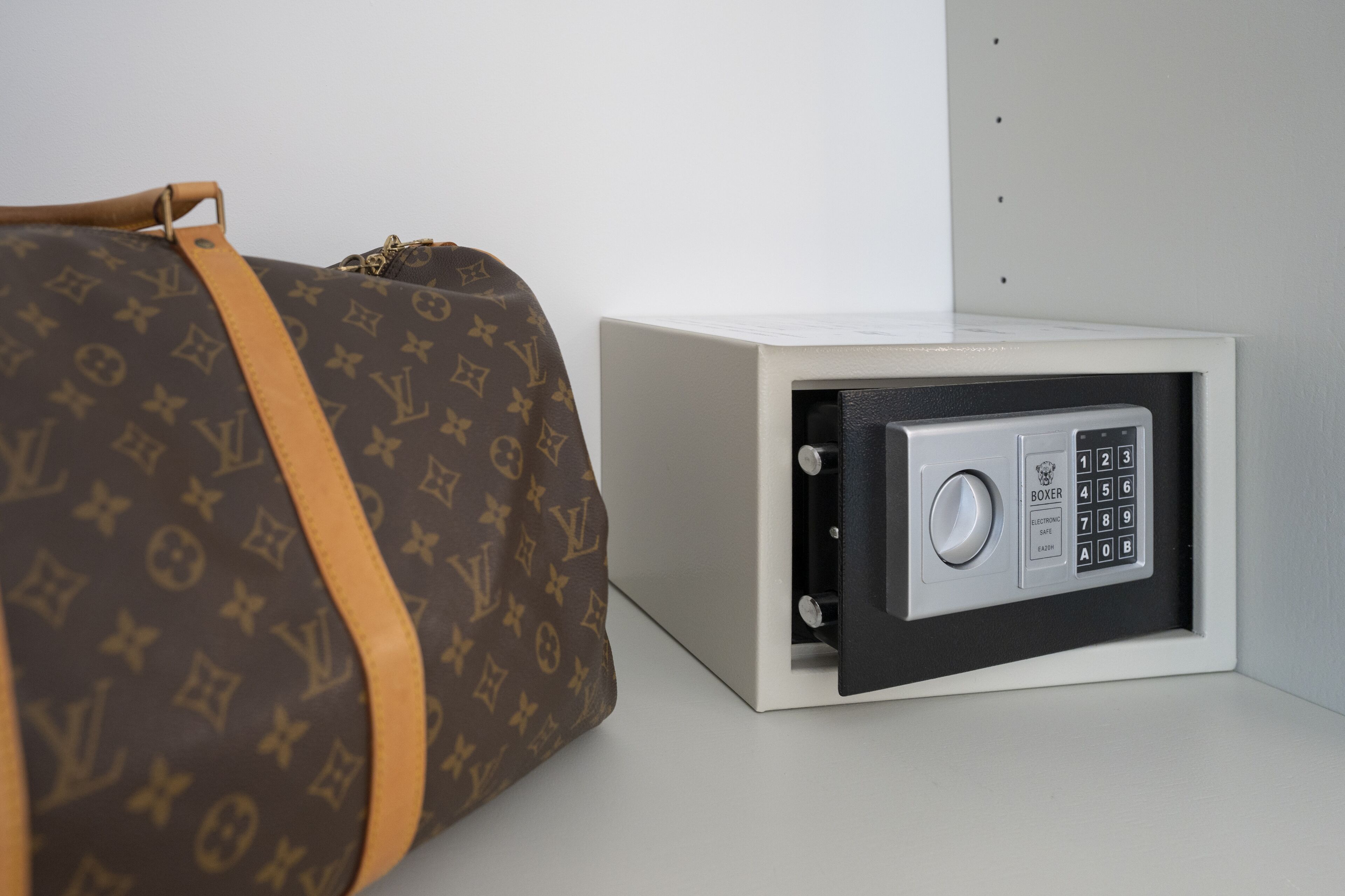 Una caja fuerte con teclado y un bolso marrón de Louis Vuitton a su lado.