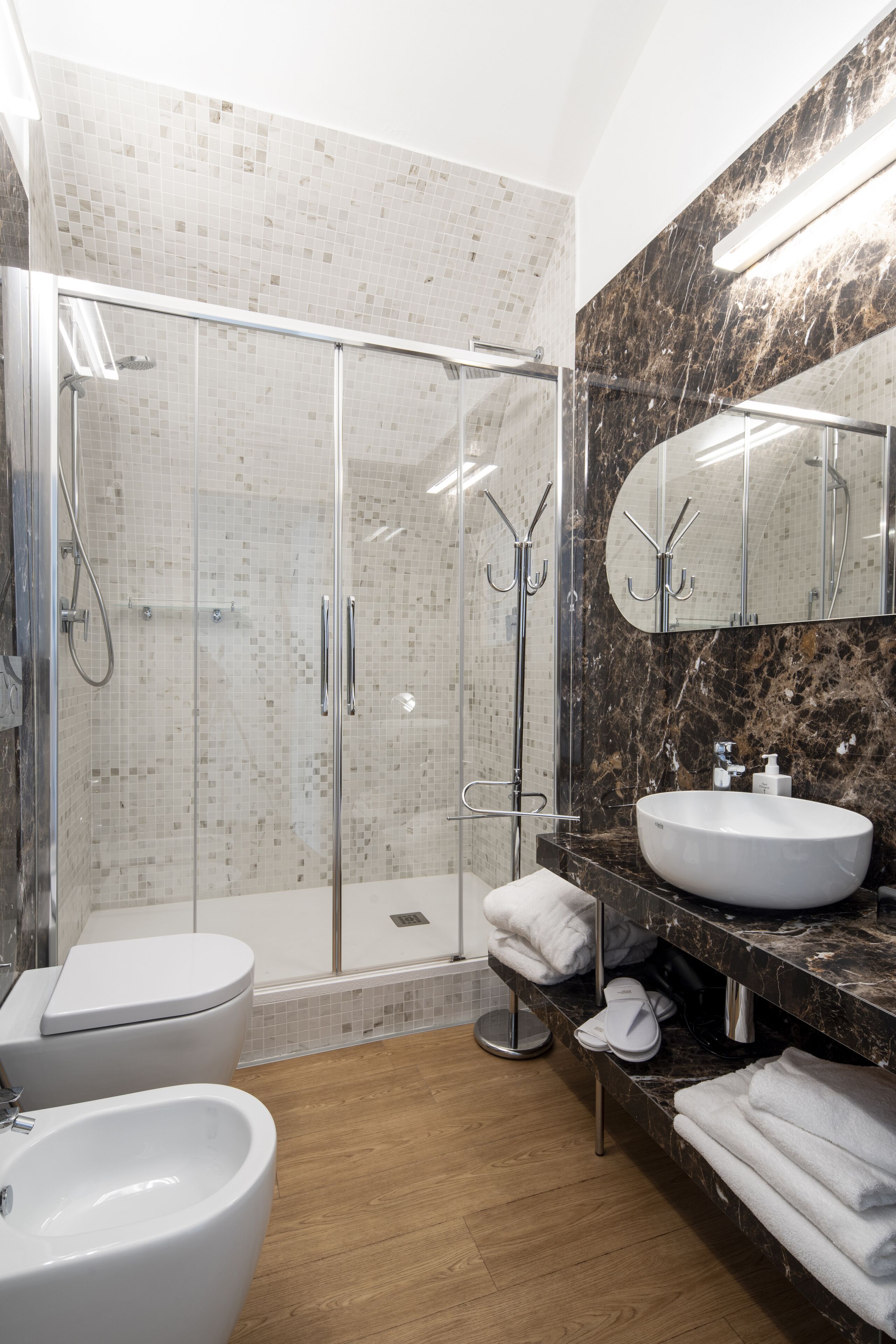 Un baño moderno con ducha de vidrio, lavamanos blanco y encimera de mármol.