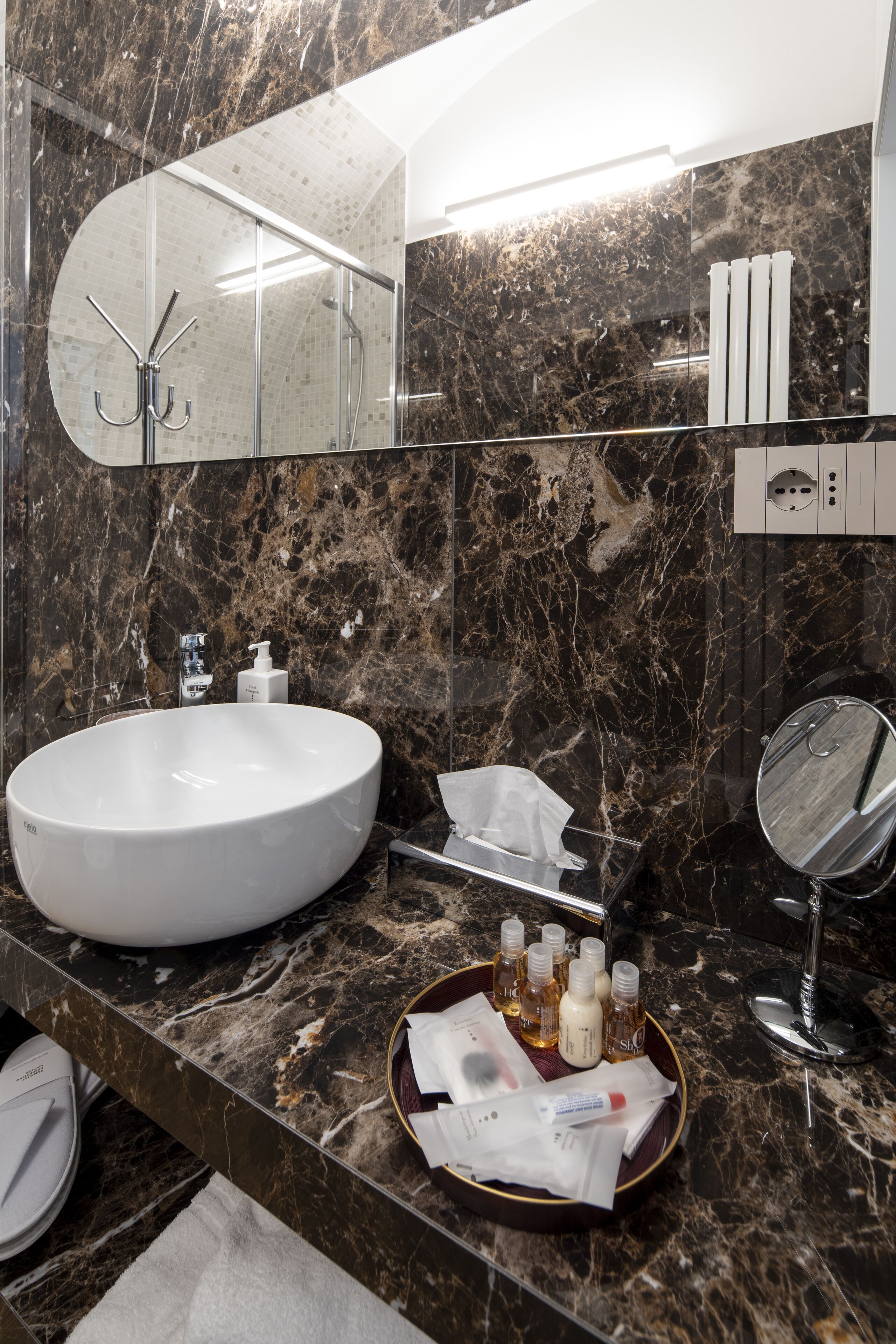 Un baño moderno con un lavabo ovalado grande, un espejo y artículos de aseo en la encimera.