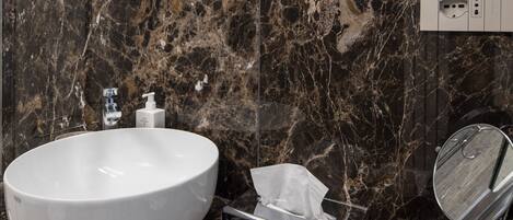 Un baño moderno con un lavabo ovalado grande, un espejo y artículos de aseo en la encimera.