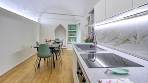 A modern kitchen with a marble backsplash, a built-in sink, and a dining area with a table and chairs. - Le stanze del Savonarola  (Ferrara)