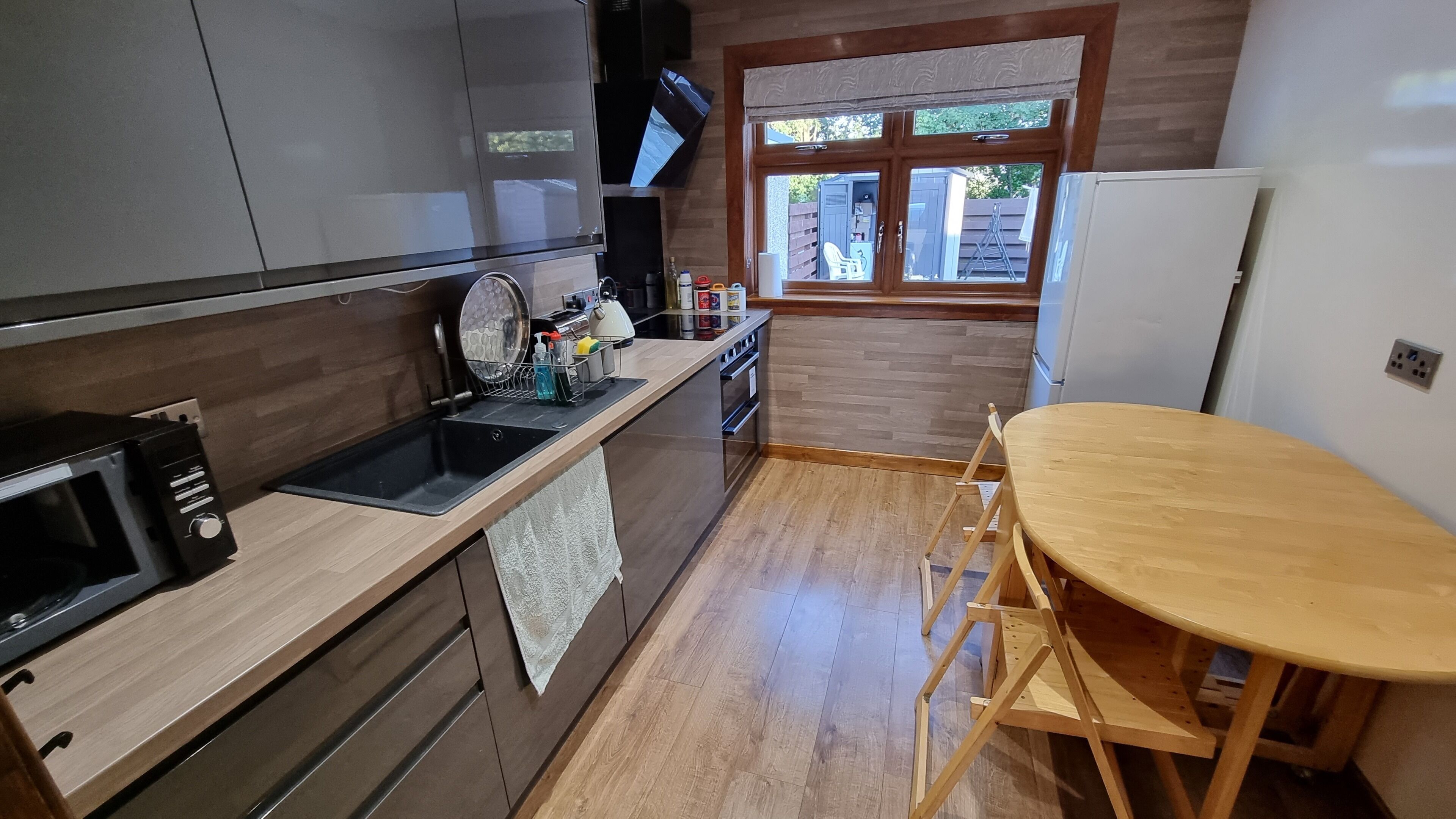 Una cocina compacta con microondas, pileta y mesa de madera.