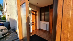 A hallway with a wooden door, a radiator, and a black mat. - Captivating 1-bed Apartment in Edinburgh (Edinburgh)